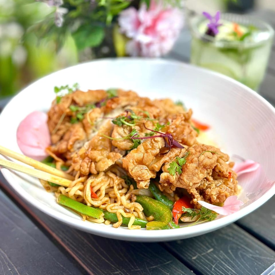 Delicious Thai Kitchen's crispy fried chicken with noodles, green beans, and red peppers.