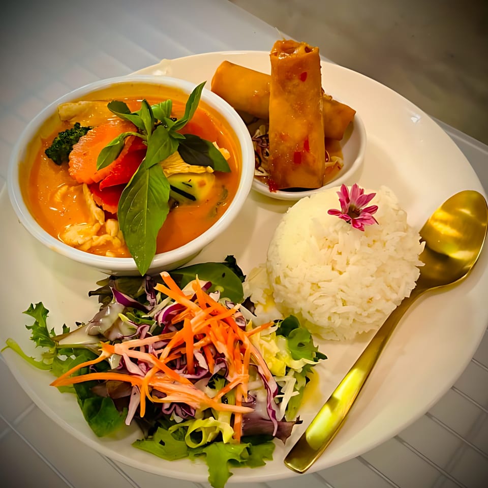 Delicious Thai Kitchen's red curry with rice, spring rolls, and a fresh salad.